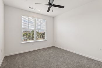 A room with a ceiling fan and a window with blinds.